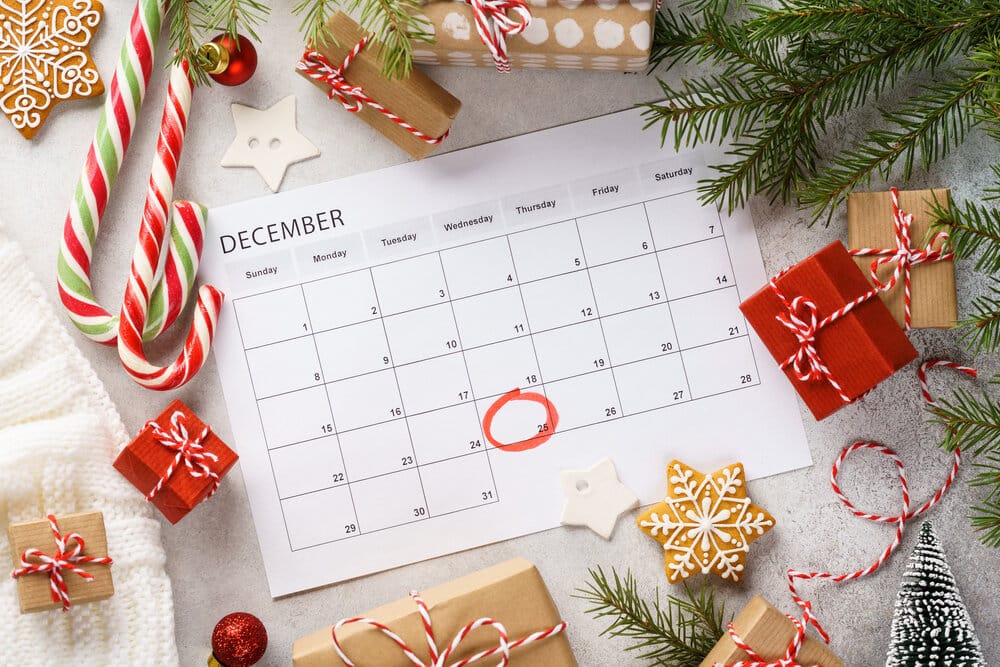 Planner page with Christmas gift boxes and decoration around. 25th of December marked with red circle on calendar. Xmas preparation concept.