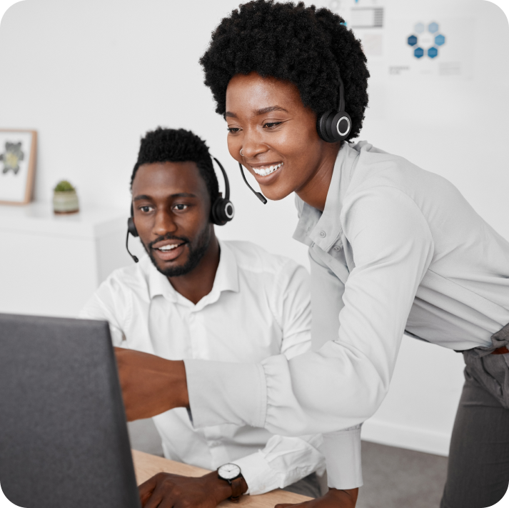 Two customer support agents wearing headsets and watching the screen in an office.