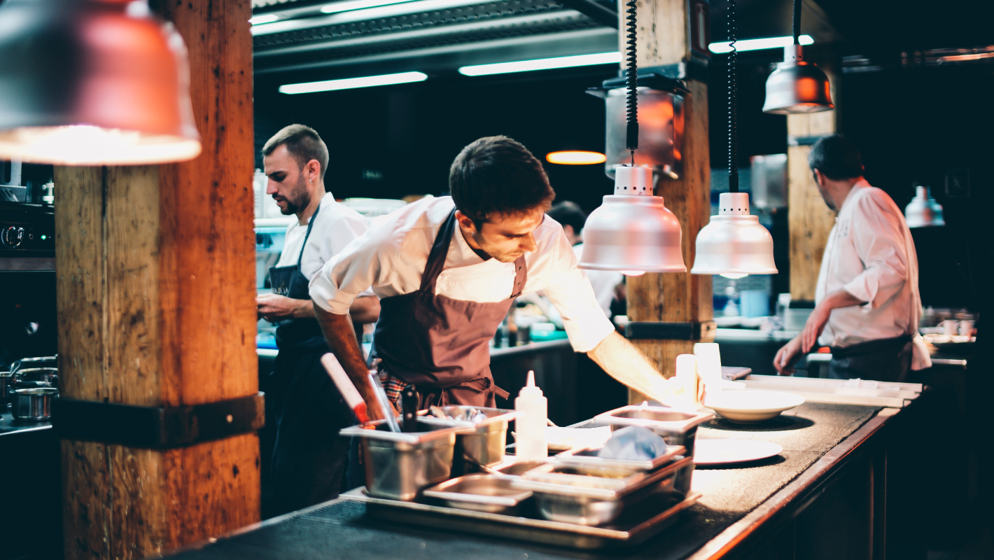 Cook serving food on a plate in the kitchen.