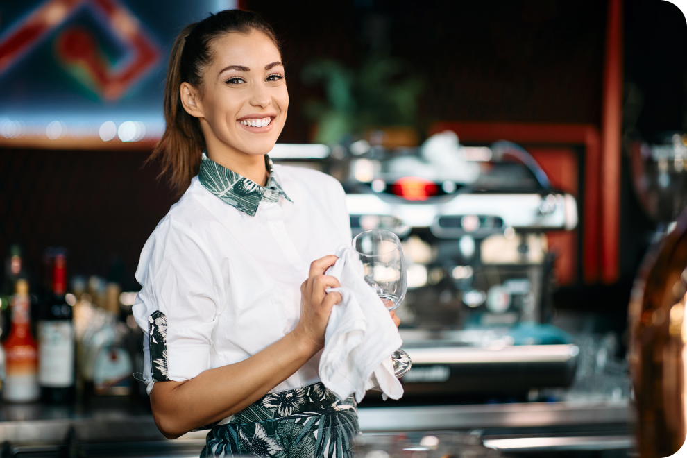 A happy female bartender is cleaning the glass.