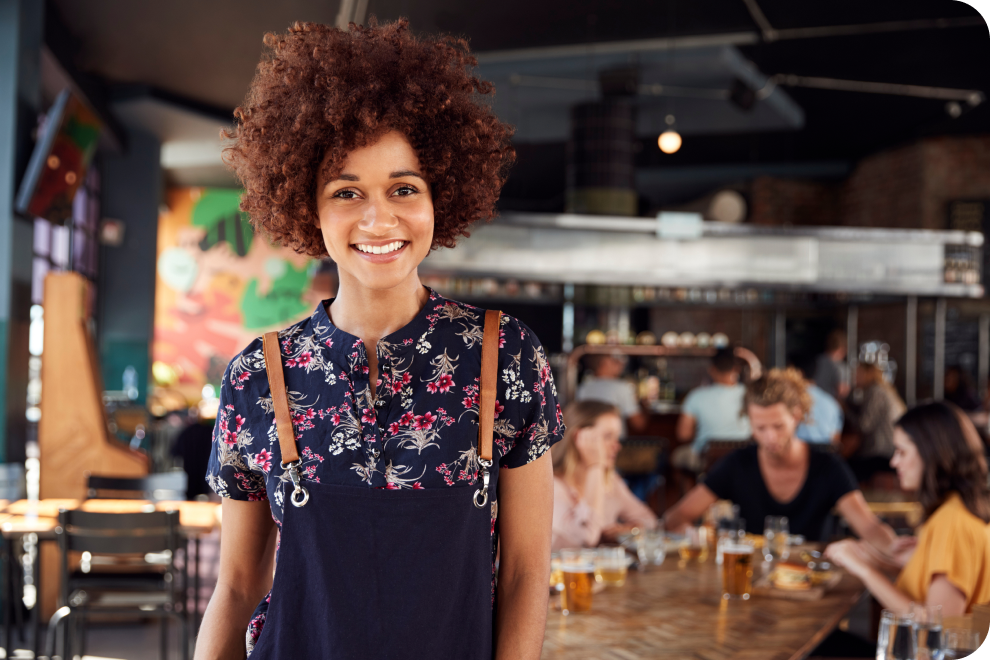 A female employee wearing an apron is standing at the full service restaurant.