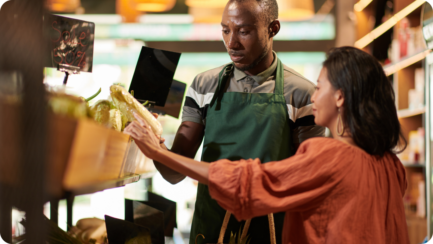 An employee helping a customer to pick up groceries in a grocery store.