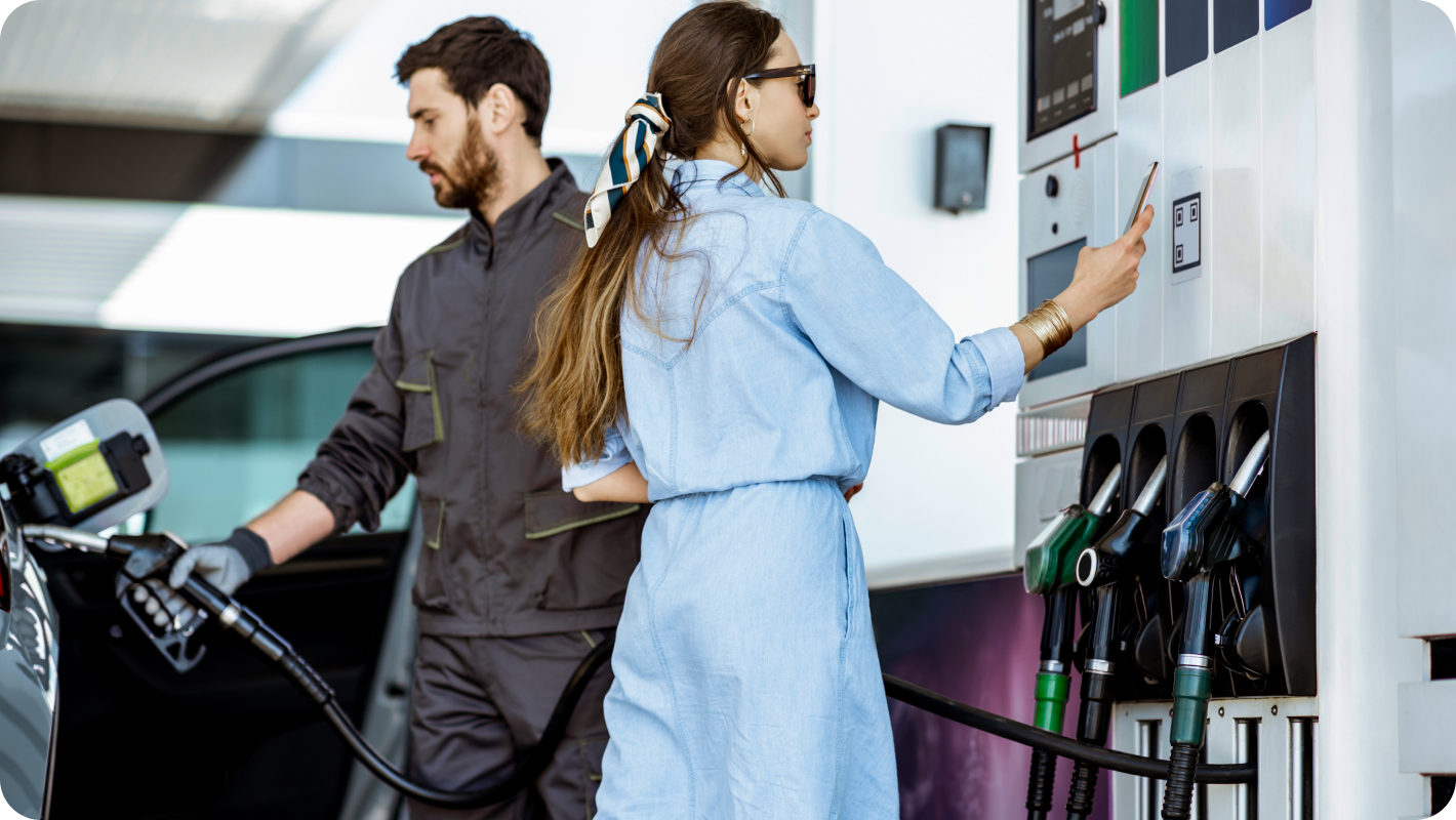 A Woman paying through a QR code scanner at the gas station.