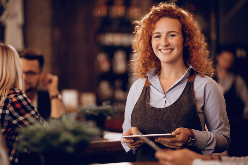 A waitress standing in the fast-casual restaurant is holding a tablet.