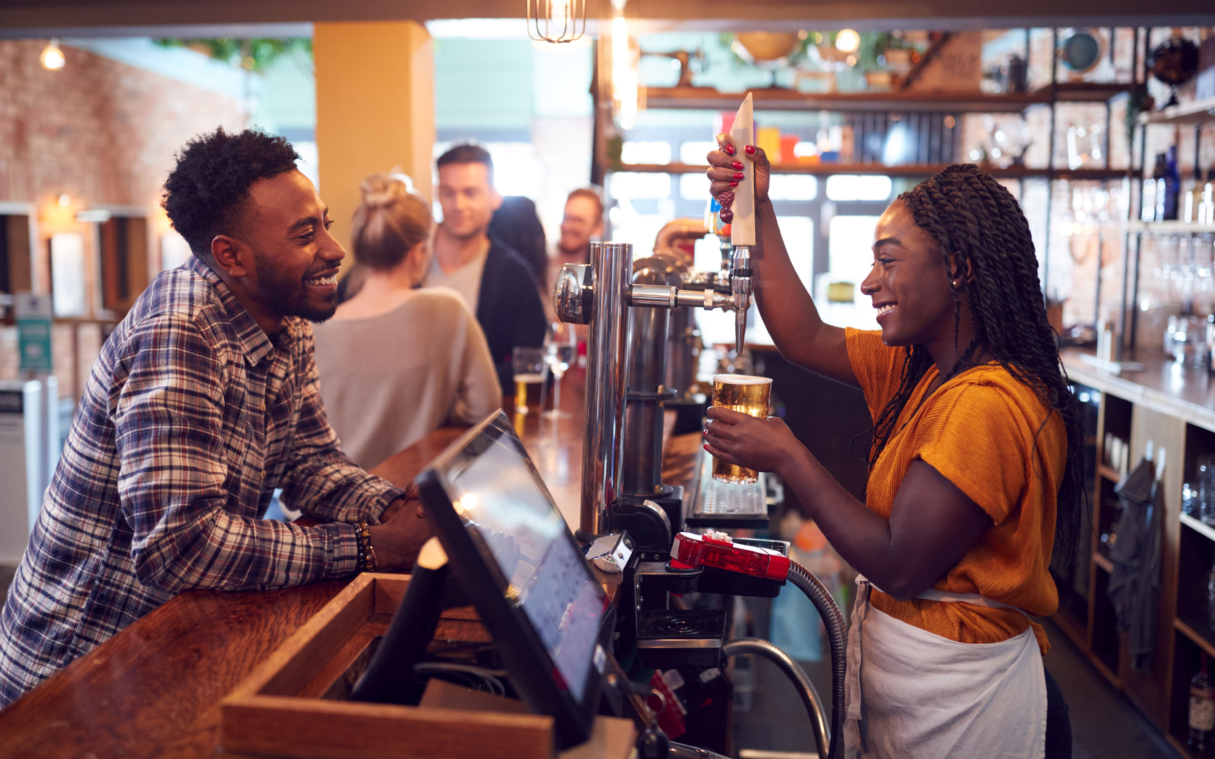 Bar owner pouring a drink for a customer.