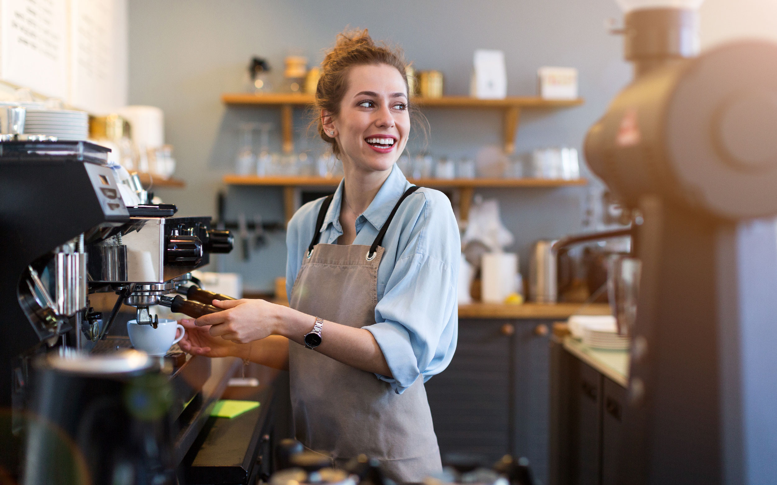 Coffee shop owner smiling while making coffee.